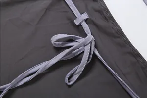 Détail du cordon de serrage latéral réglable sur un ensemble jupe et haut gris.