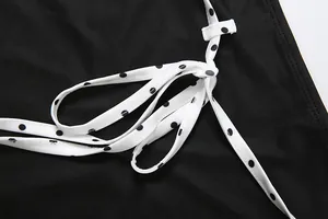 Détail du nœud blanc à pois sur un vêtement en tissu noir