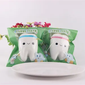 Detail of two smiling white tooth squishy toys in green I LOVE TEETH packaging