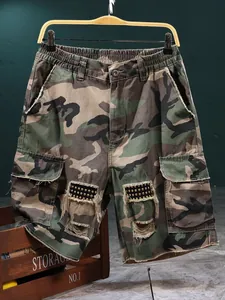 Macro view of men's camouflage tactical cargo shorts featuring distressed hole details