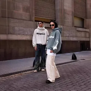 Due modelli indossano felpe streetwear oversize con motivi a stella in una strada.