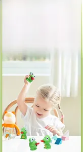 Close-up of child playing with green frog and dinosaur squeeze toys on a table