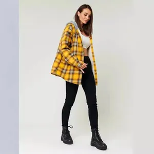 Vista a figura intera di una donna con giacca a quadri gialla con cappuccio e stivali