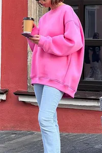 Primo piano di una felpa oversize in pile rosa acceso indossata da una modella su strada