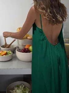 Back detail of a green backless spaghetti strap maxi dress in a lifestyle kitchen setting