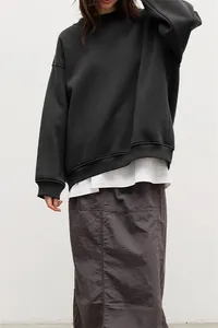 Dettaglio di una felpa nera girocollo ampia da donna con uno stile minimalista ed elegante.