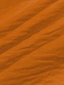 Detailed macro view of orange ice silk crinkle fabric texture for summer beach dress
