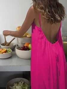Back view of a vibrant pink backless maxi dress with delicate spaghetti straps.
