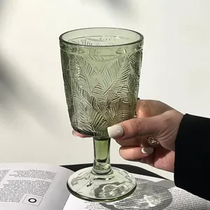 Vue détaillée d'un élégant verre à pied vert vintage avec motif de feuilles en relief