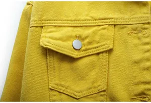 Primer plano detallado de un bolsillo de chaqueta vaquera amarilla con botón metal.