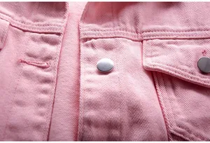 Detalle macro de una chaqueta vaquera rosa con textura de tela de alta calidad y botón metálico