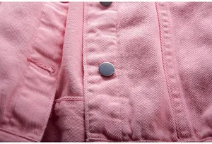 Primer plano de la textura de la tela vaquera rosa y los botones metálicos de la chaqueta.