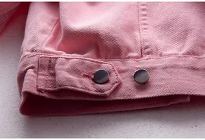 Vista detallada del dobladillo de la chaqueta vaquera rosa con botones metálicos plateados
