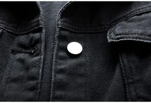 Detalle macro de una chaqueta vaquera negra que muestra la textura y el botón de metal.