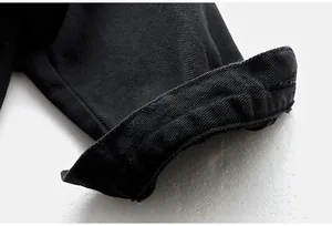 Primer plano detallado del puño remangado de una chaqueta vaquera negra oversize