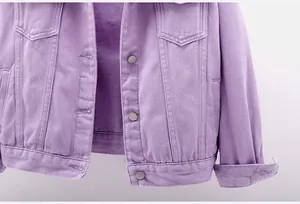 Detalle de una chaqueta vaquera color lavanda con botones metálicos y costuras.