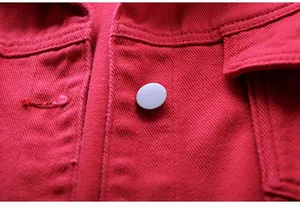 Detalle de una chaqueta vaquera roja que muestra la textura del tejido y el botón metálico.