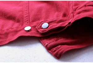 Primer plano del dobladillo de una chaqueta vaquera roja con botones de metal plateado