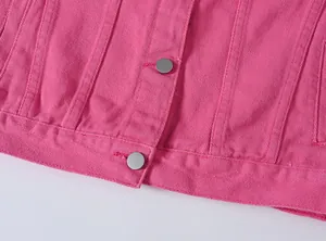 Primer plano del dobladillo de una chaqueta vaquera rosa con botones metálicos plata.
