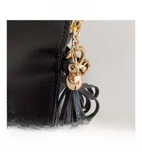 Detail of stylish gold zipper pull and leather tassel on a black PU crossbody bag.