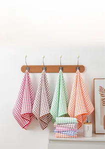 Veelkleurige geruite katoenen theedoeken hangend aan een houten wandrek in de keuken.