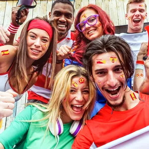 Group of football fans celebrating with Spain flag temporary tattoos at World Cup party.