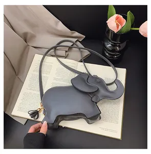 Detailed view of a grey elephant-shaped crossbody bag on an open book background.