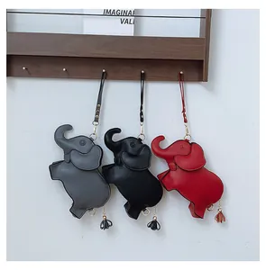 Three colors of cute elephant-shaped PU leather handbags with tassels hanging on a rack