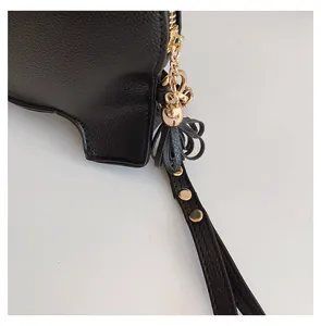 Close-up of black cartoon elephant PU bag with gold zipper and studded wristlet strap.