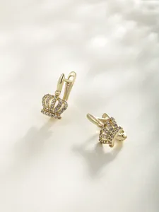 Close-up macro view of gold crown-shaped hoop earrings decorated with sparkling clear stones