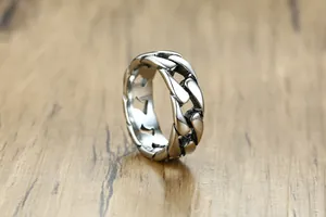 Vue détaillée d'une bague en acier titane à maillons cubains sur un fond de bois rustique