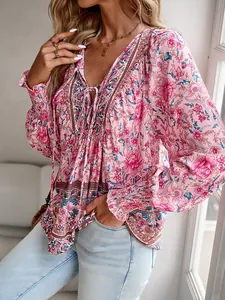 Détail d'une blouse bohème à fleurs roses avec col en V et lien de nouage élégant.