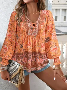 Détail de la blouse bohème à imprimé fleuri, col en V, liens et poignets smockés.