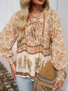 Détail d'une blouse bohème à fleurs avec col en V à nouer et poignets smockés pour femme.