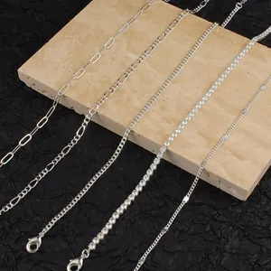 Close-up detail of five silver-toned anklet styles including tennis chain and paperclip link