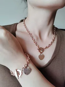Gros plan d'un ensemble collier et bracelet en acier inoxydable or rose avec cœurs