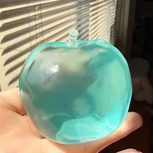 Primo piano di un giocattolo antistress a forma di mela blu traslucido in mano