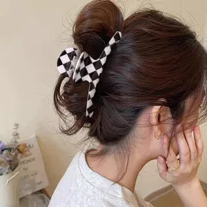 Side view of woman wearing a black and white checkerboard hair claw clip in a bun