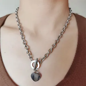 Vue détaillée d'un collier cœur en acier inoxydable avec fermoir en T porté par un mannequin