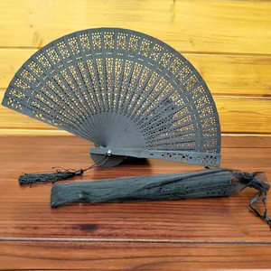 Detailed view of black hollow-out wooden folding fan featuring tassel and mesh storage bag