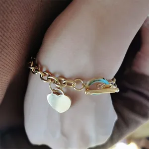 Gros plan d'un bracelet en acier inoxydable doré avec breloque cœur et fermoir à bascule bleu