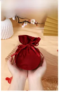 Elegant red velvet drawstring gift bag being held, perfect for wedding favors and small gifts.