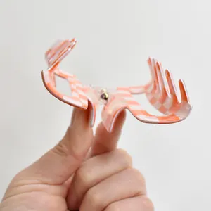 Detailed view of an orange and white checkerboard patterned hair claw clip held by a hand