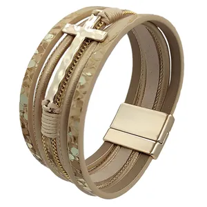 Close-up of multi-layer leather bracelet with gold cross and magnetic clasp