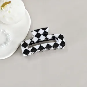 Detailed view of a stylish black and white checkerboard square hair claw clip accessory
