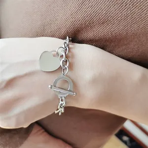 Détail d'un bracelet en acier inoxydable argenté avec pendentif cœur et fermoir T
