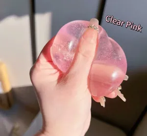 Primo piano di un giocattolo squishy mela rosa trasparente schiacciato a mano