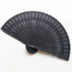 Close-up detail of an elegant black hollow carved wooden folding fan for wedding dancing