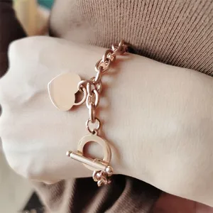 Gros plan d'un bracelet à breloque cœur en acier rose doré avec fermoir T