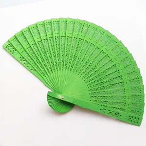 Detailed view of a bright green hollowed-out wooden folding fan with intricate carvings